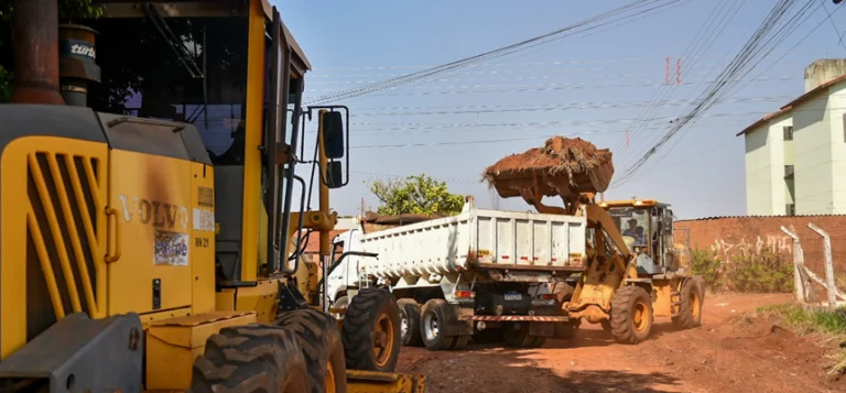 Obras de pavimentação no Bairro Nova Lima, Campo Grande, com máquinas e trabalhadores em ação, melhorando a infraestrutura das ruas.